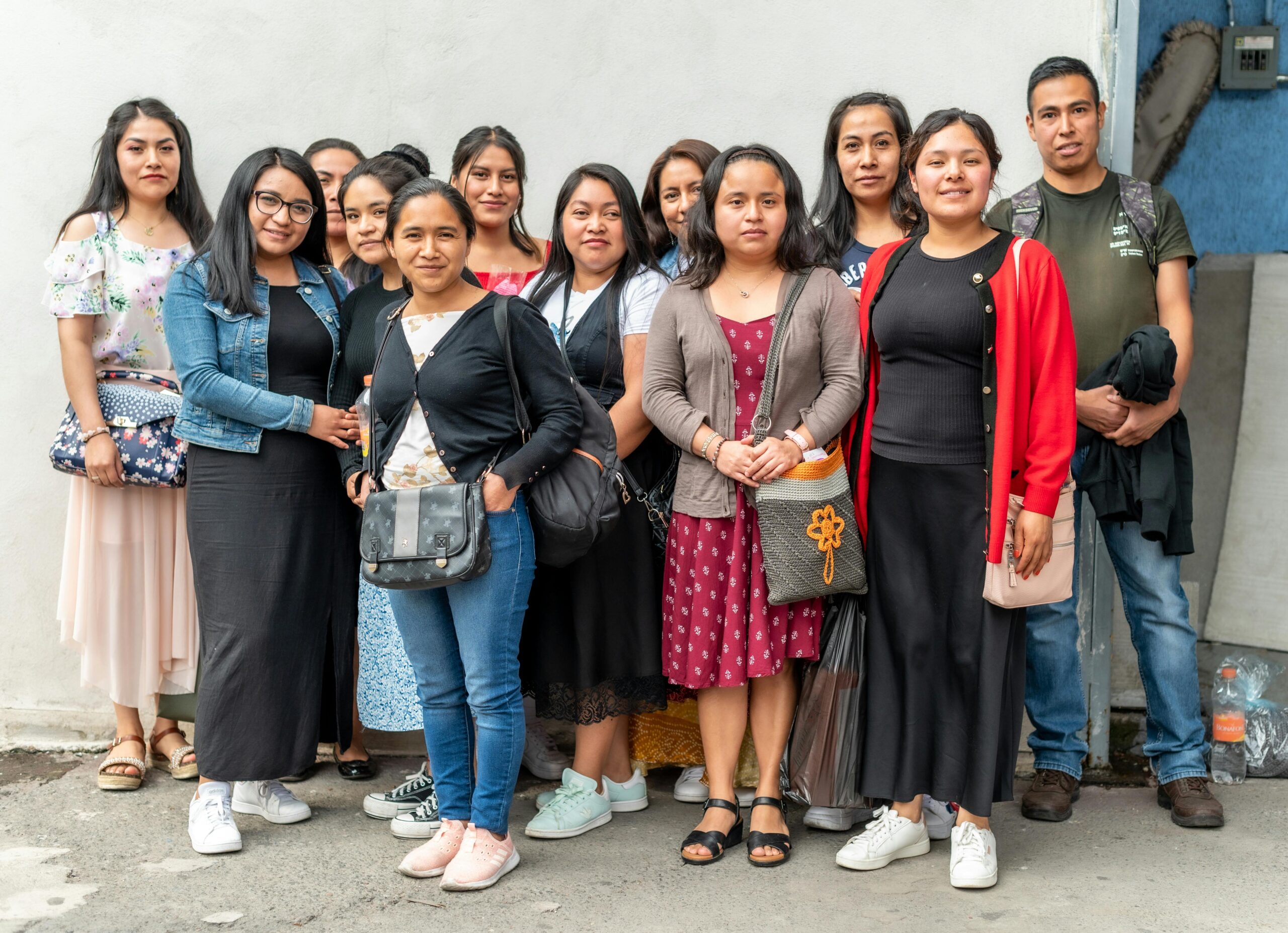 A diverse group of young adults standing together outdoors, smiling and casual.